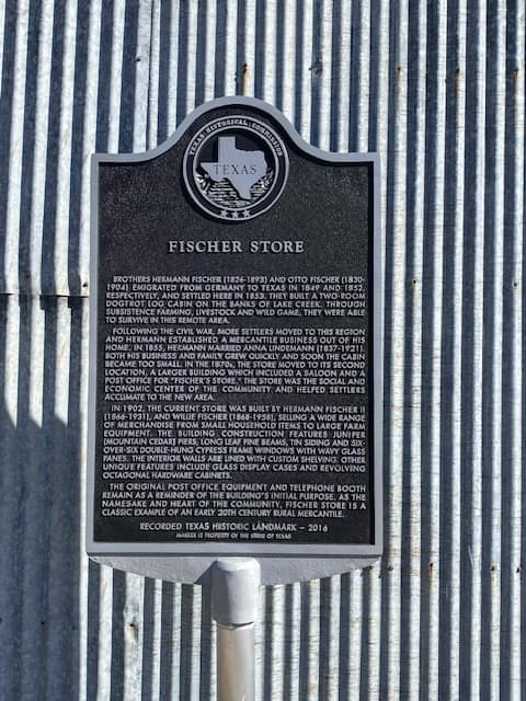 The Texas Historical Commission marker for the Fischer Store, on its corrugated-tin wall