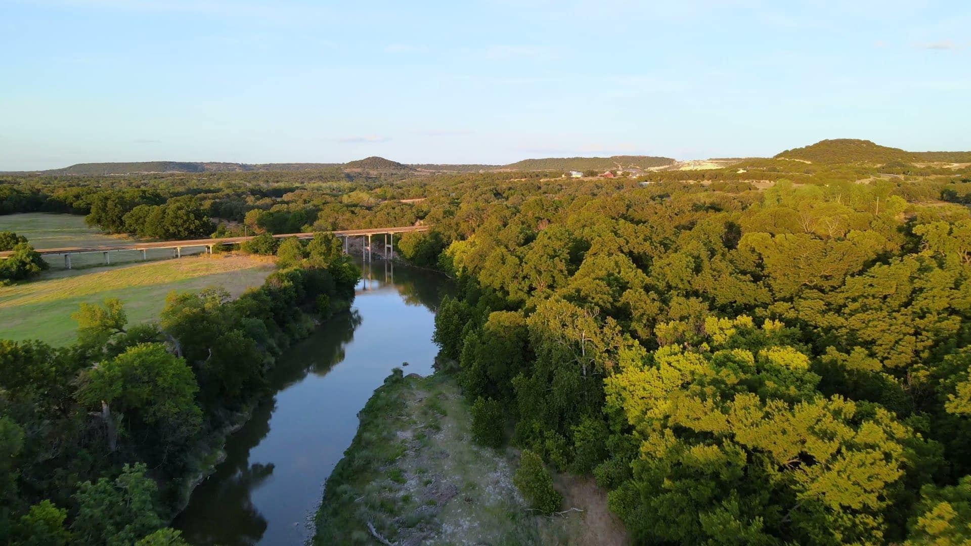 A Hill Country river winding through live oaks at golden hour